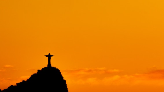 Silhueta do Cristo Redentor, Rio de Janeiro, com céu em tons de laranja