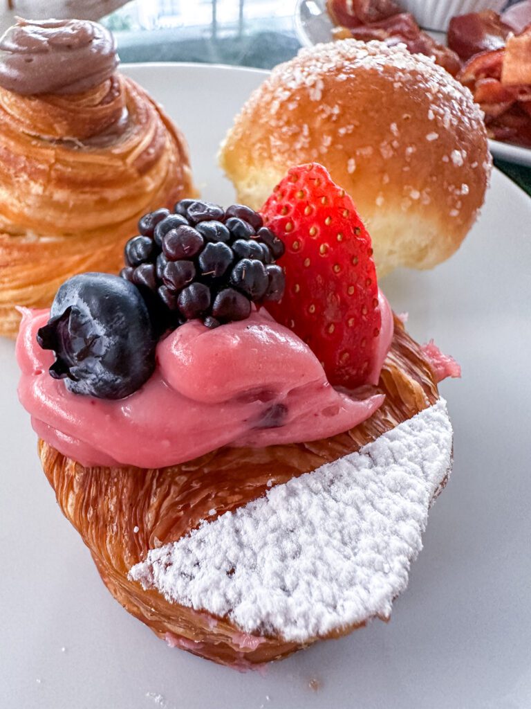 tr&ecirc;s p&atilde;ezinhos do caf&eacute; da manh&atilde; do &agrave; frente, um folhado coberto com um creme rosa e frutas vermelhas
