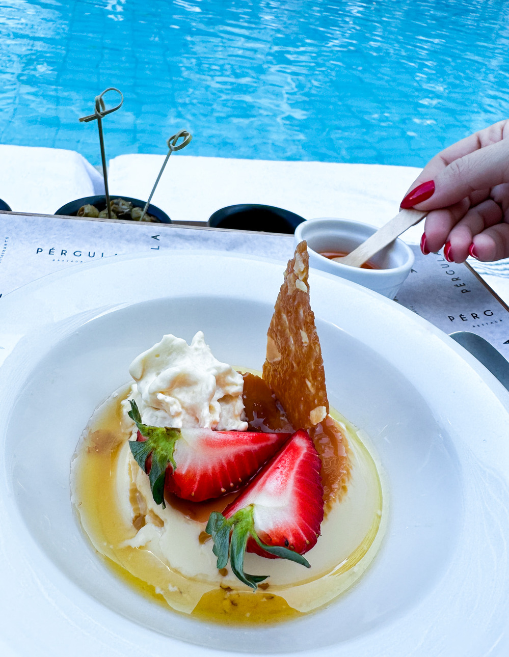 Prato com pudim de leite, morango e chantilly, servido &agrave; beira da piscina